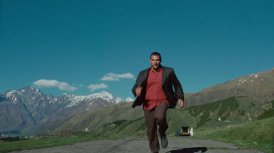 a man in a red shirt is running down a road