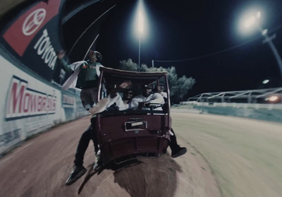 a man riding in the back of a buggy down a dirt road