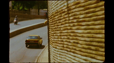 a car driving down a street next to a wall