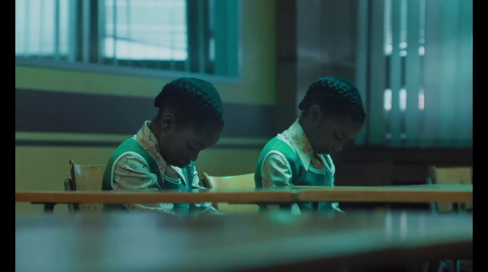 two young girls sitting at desks in a classroom