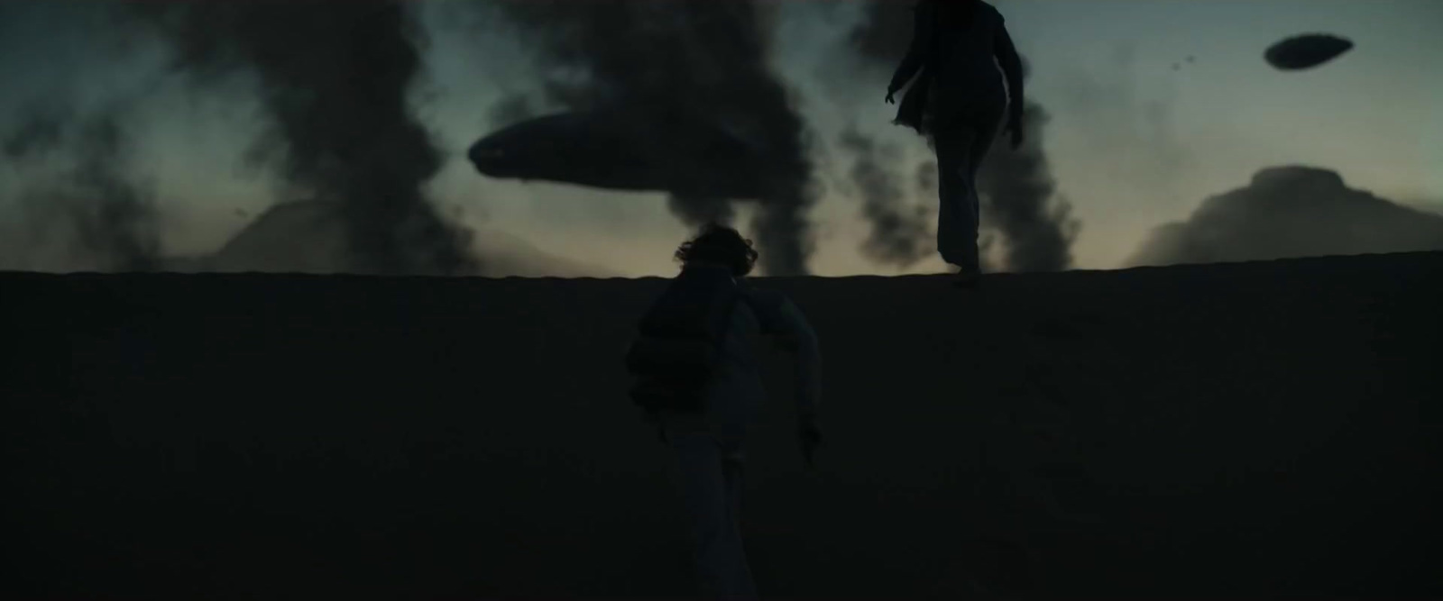 a person standing on a hill with a frisbee in the air