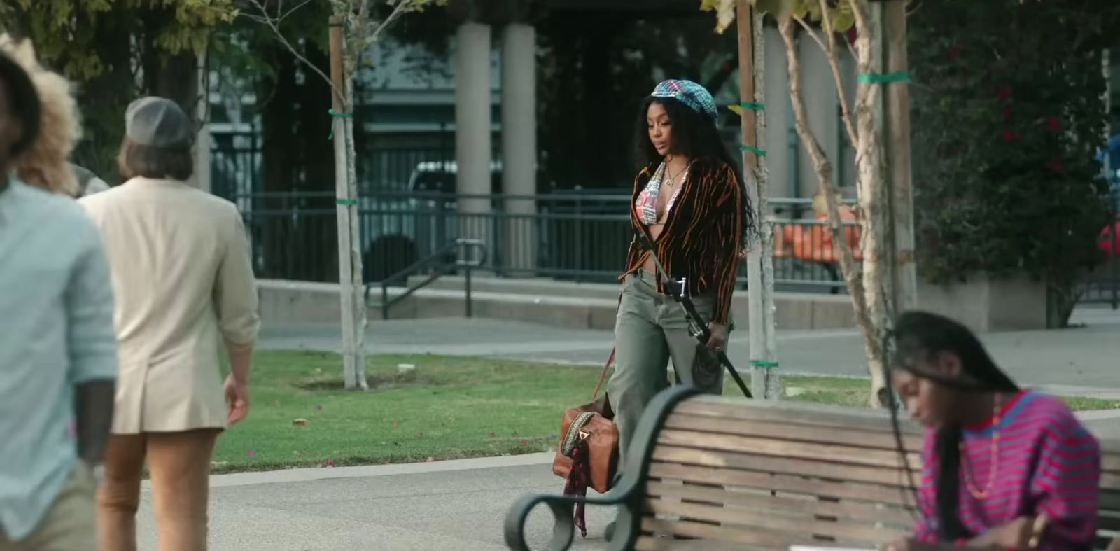 a woman walking down a sidewalk next to a park bench