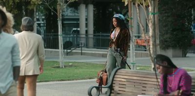 a woman walking down a sidewalk next to a park bench