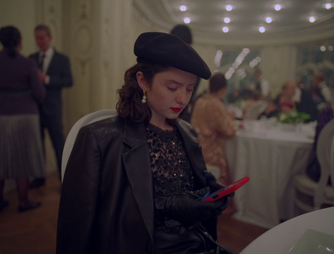 a woman in a black hat is looking at her cell phone