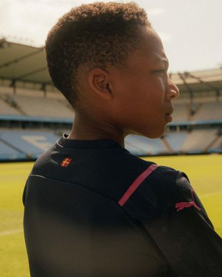 a young boy standing in front of a soccer field