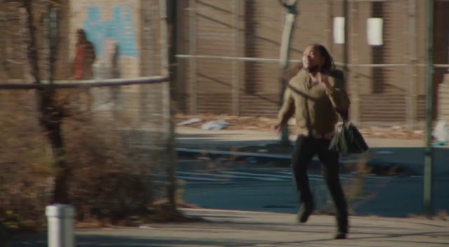 a woman walking down a sidewalk carrying a purse