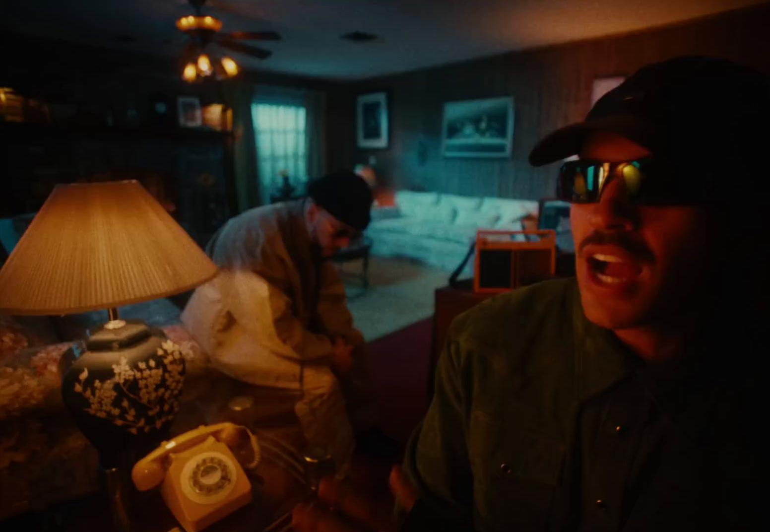 a man wearing sunglasses and a hat in a living room