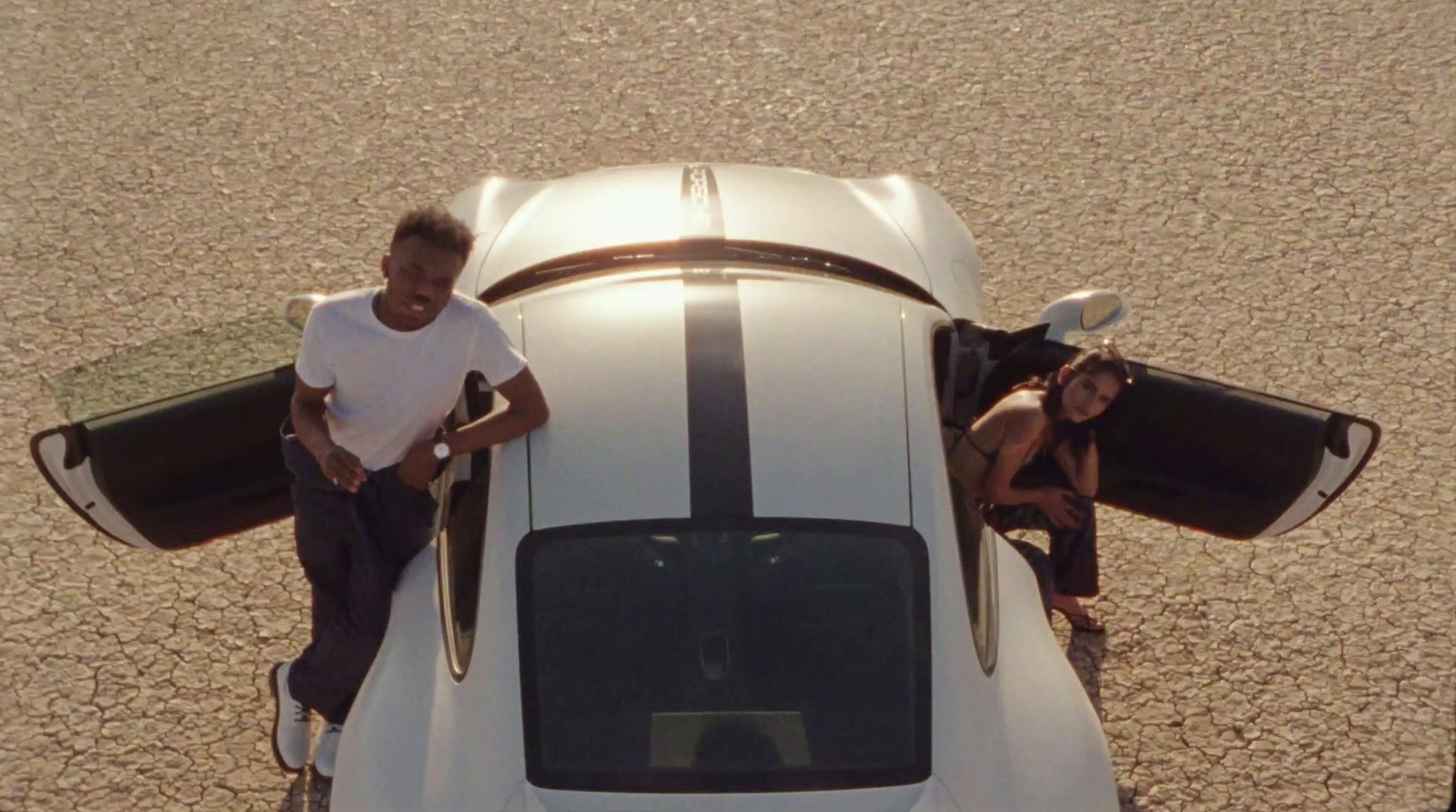 a man standing on top of a white sports car