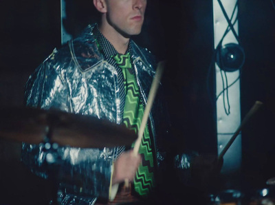 a man with a green tie playing drums