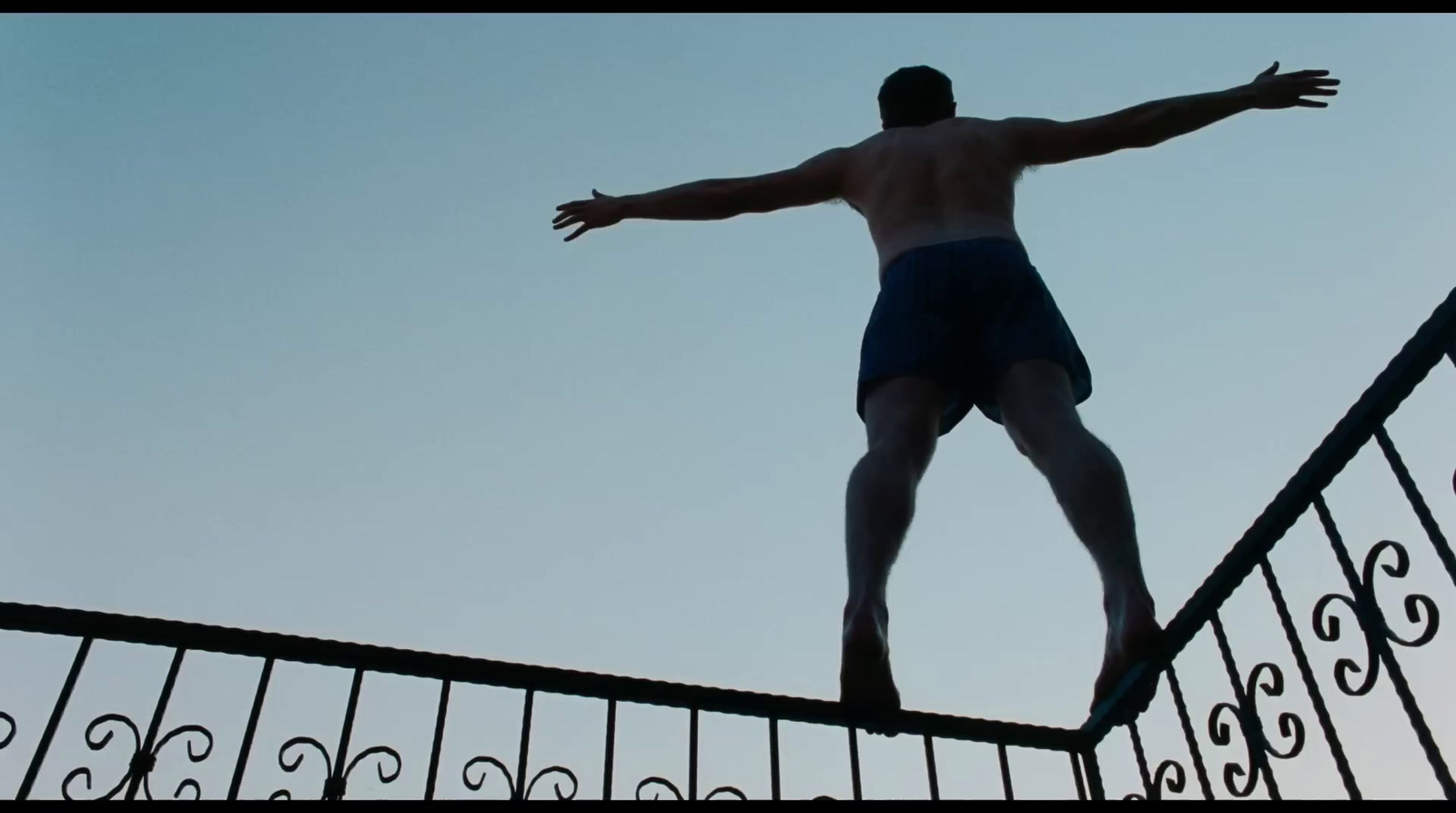 a man standing on a railing with his arms outstretched