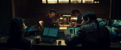 a group of people sitting around a table with laptops