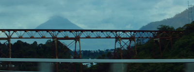 a train traveling over a bridge with mountains in the background