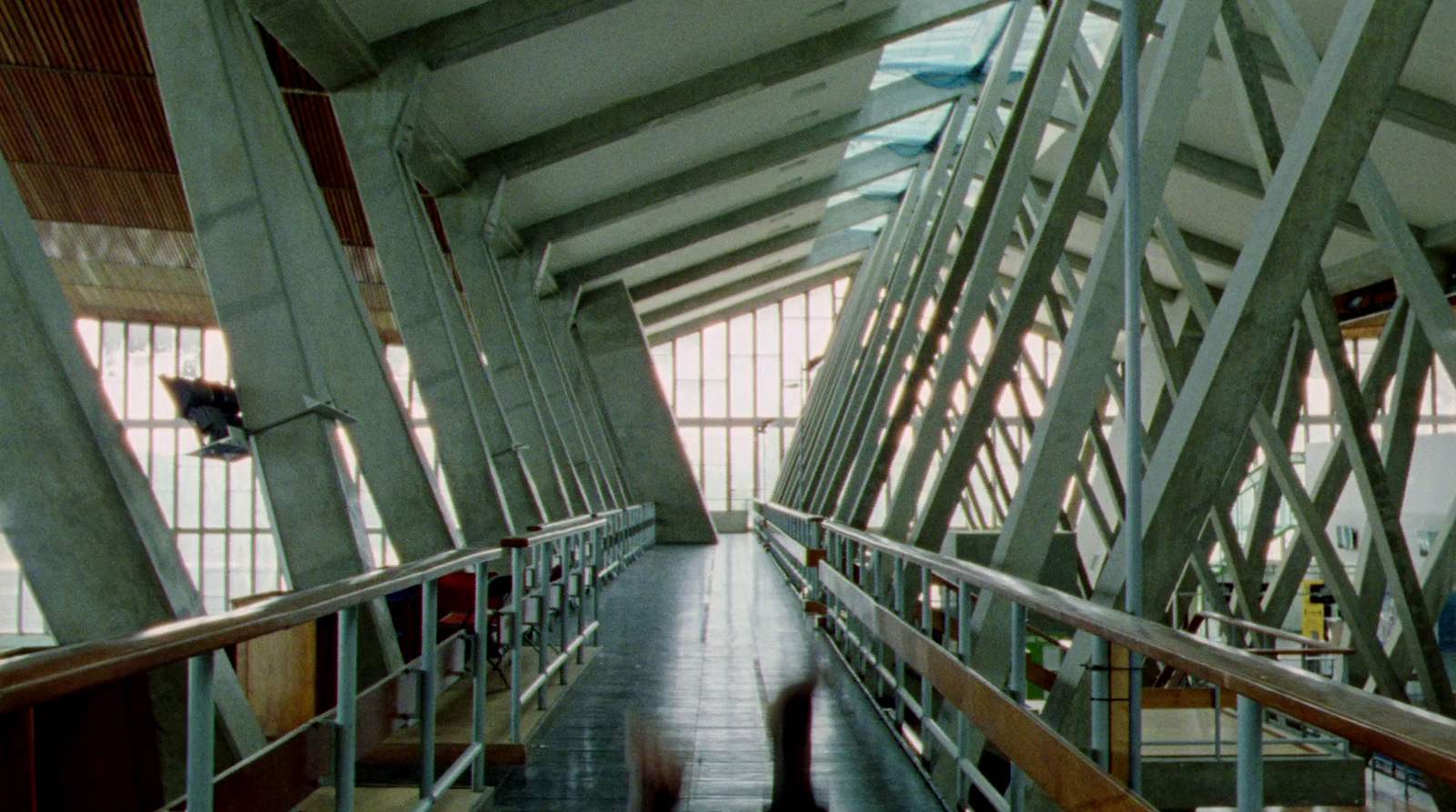 a person is walking down a walkway in a building