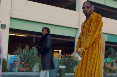 a man in a yellow robe and sunglasses standing on the street