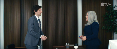 a man in a suit and tie talking to a woman in a suit