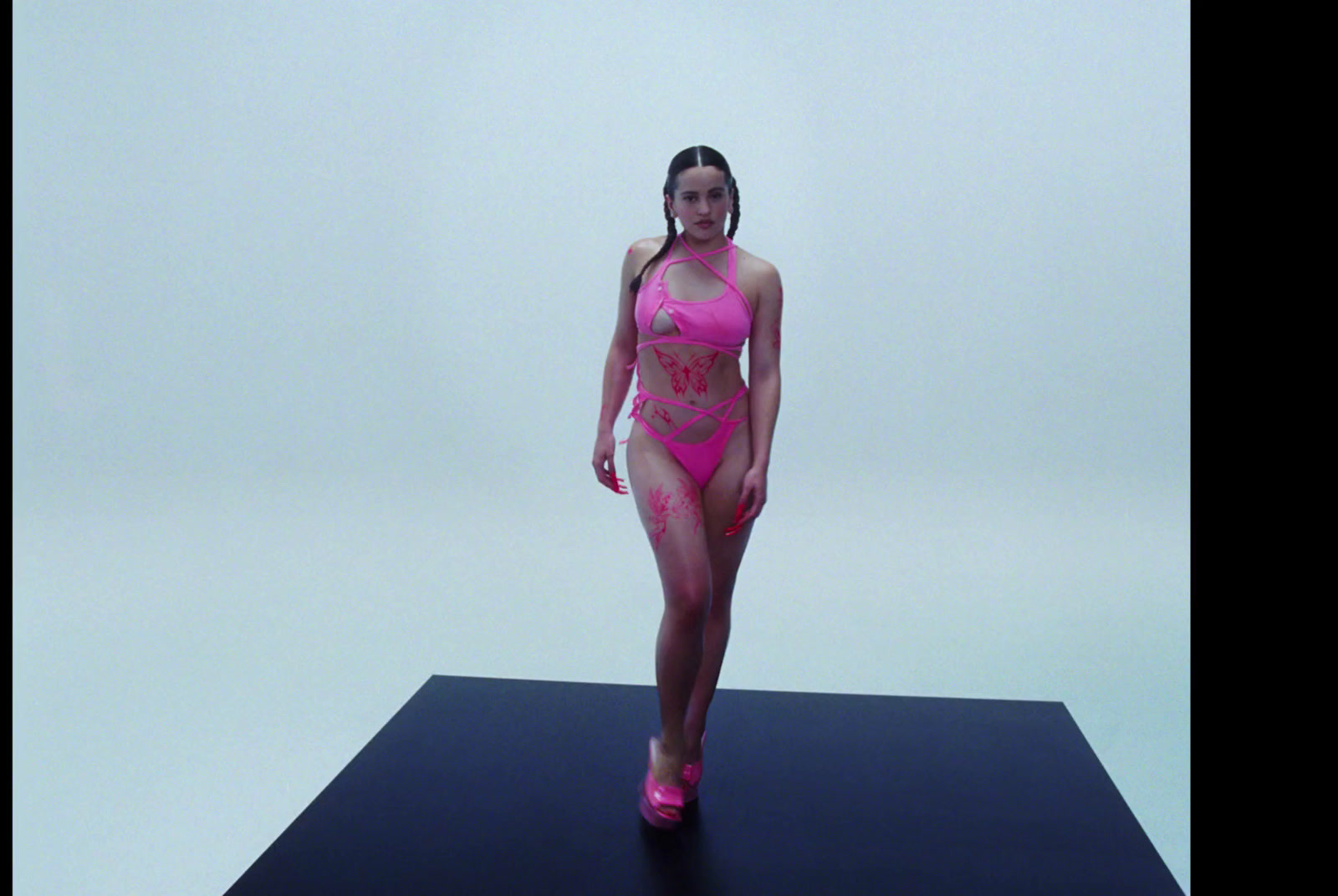 a woman in a pink swimsuit walking down a runway