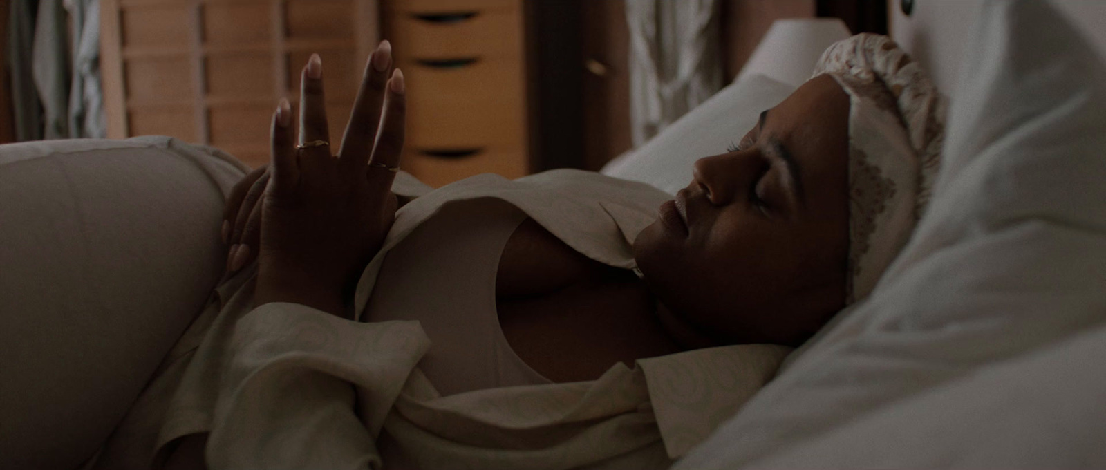 a woman laying in bed with her hands up in the air