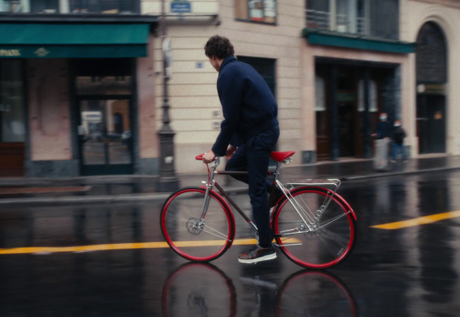 a man riding a bike down a rain soaked street