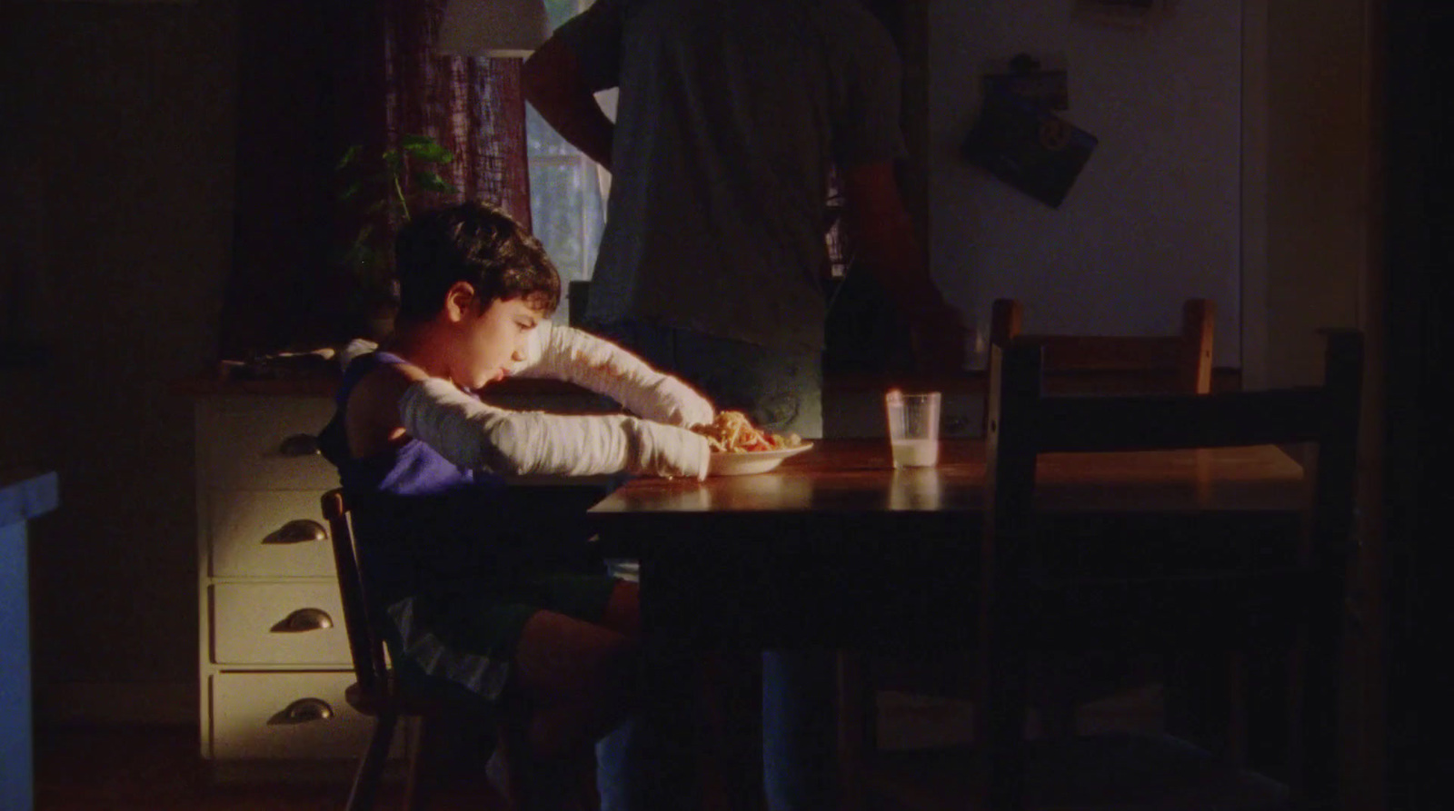 a little boy sitting at a table with a plate of food