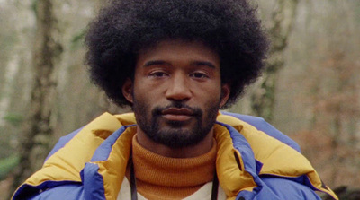 a man with an afro wearing a blue and yellow jacket