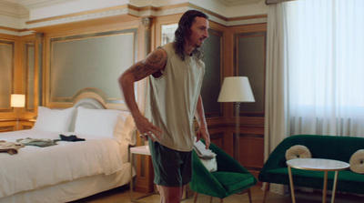 a man standing in a hotel room with a green chair