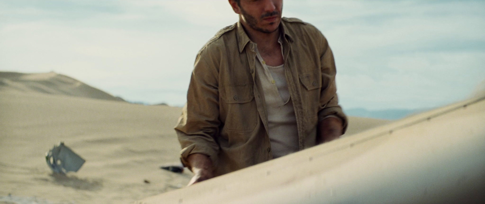 a man holding a surfboard on top of a sandy beach