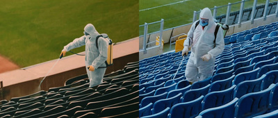 two people in hazmat suits spray disinfection at a baseball stadium