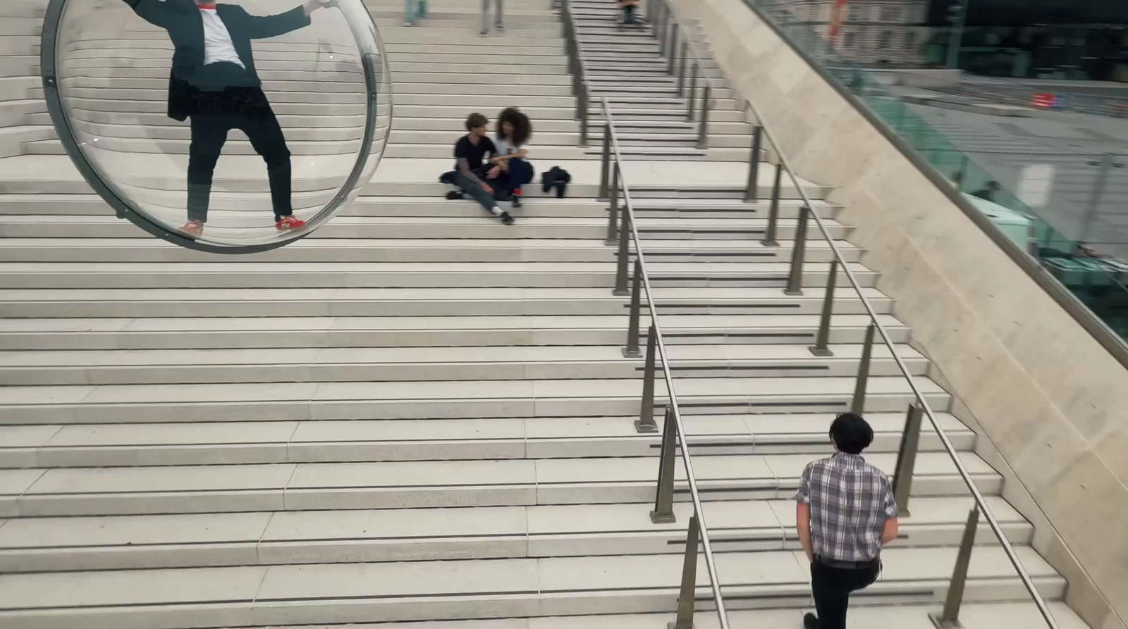 a man walking down a flight of stairs with a giant mirror hanging from the ceiling