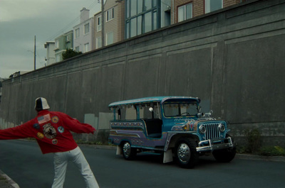 a man in a red jacket standing next to a blue bus