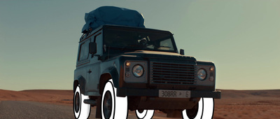 a blue land rover driving through the desert