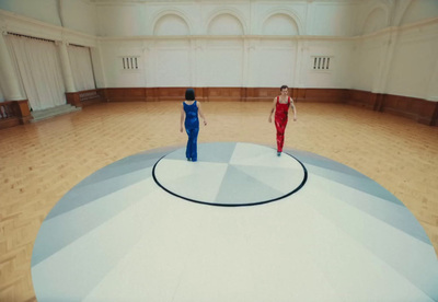 a couple of women standing on top of a wooden floor