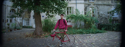 a man standing next to a red bike on a brick road