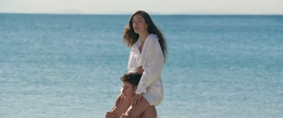 a woman standing on top of a man on the beach