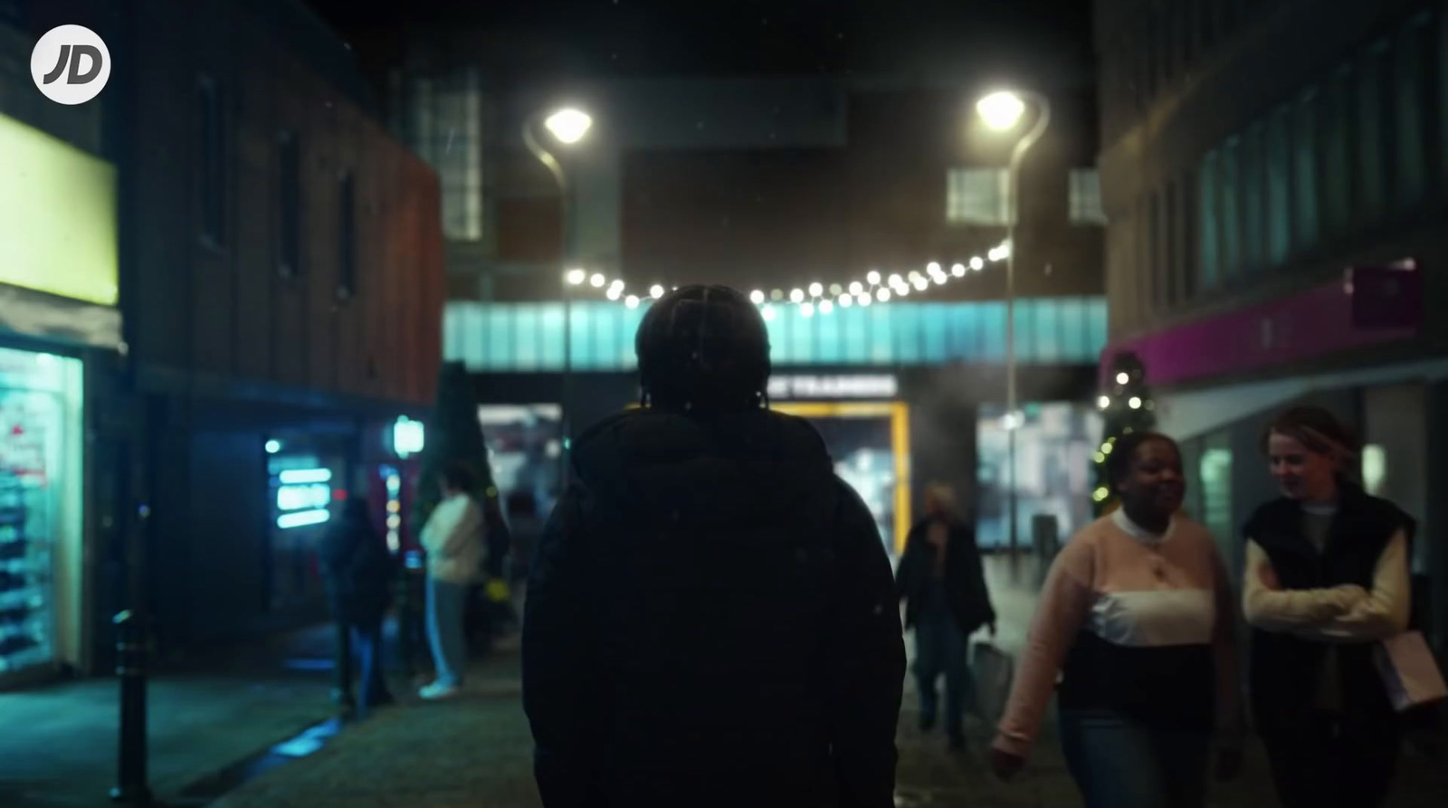 a group of people walking down a street at night