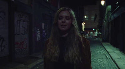 a woman walking down a street at night