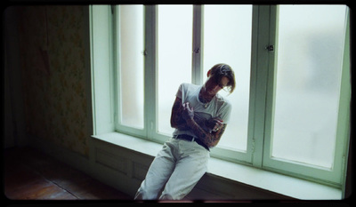 a man sitting on a window sill looking at his cell phone