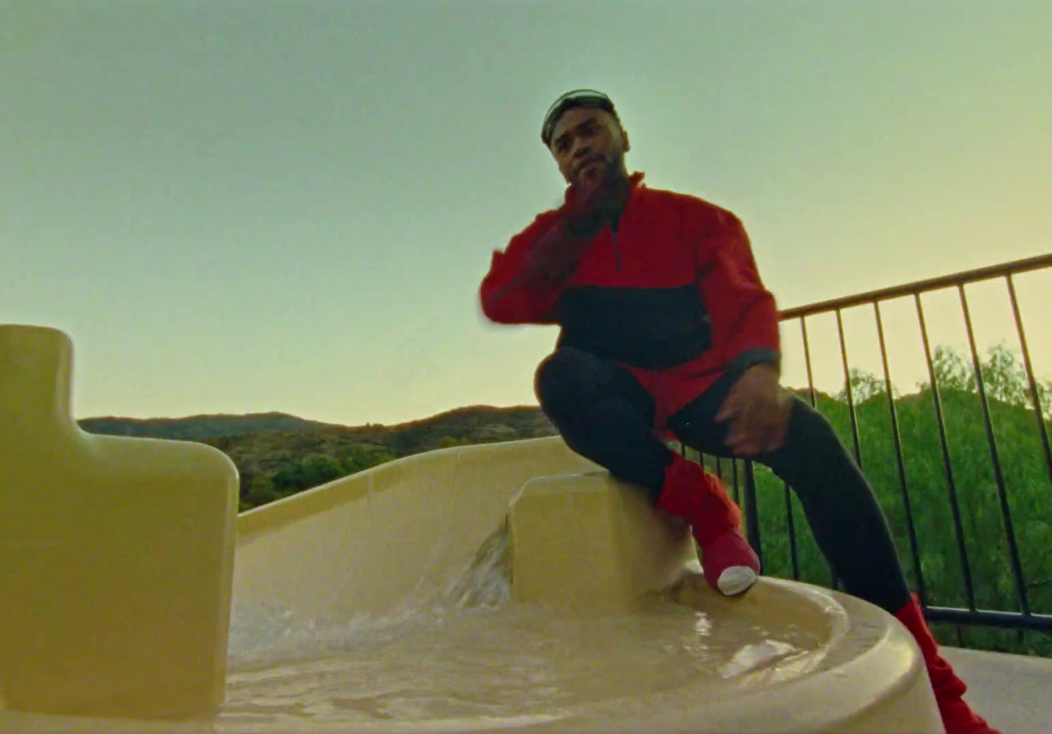 a man sitting on top of a water fountain talking on a cell phone