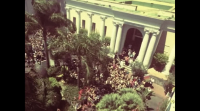 an aerial view of a crowd of people in front of a building