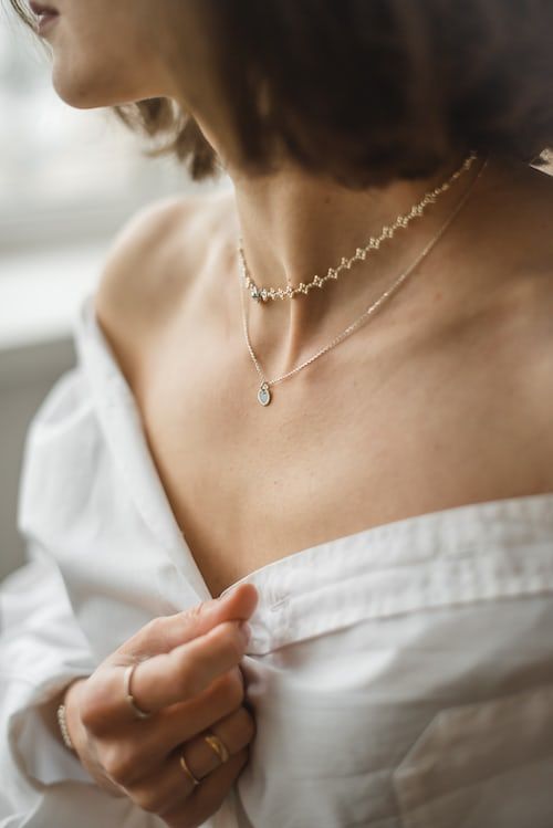 a woman in a white dress is wearing a necklace