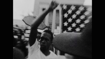 a black and white photo of a man holding an american flag