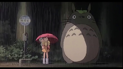 a person holding an umbrella standing next to a totoro