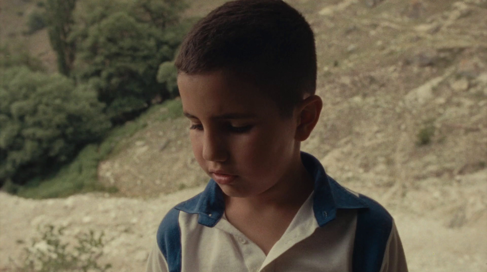 a young boy looking down at his cell phone