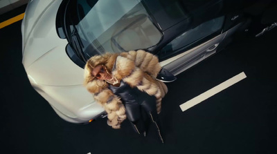 a woman in a fur coat standing next to a car