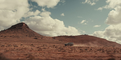 a truck driving down a dirt road in the desert