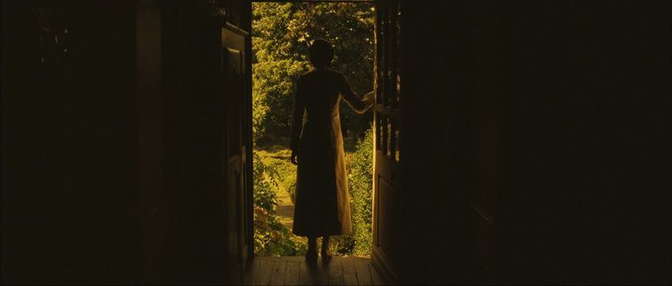 a woman in a long coat is standing in an open doorway