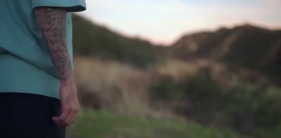 a man with a tattoo on his arm standing in a field