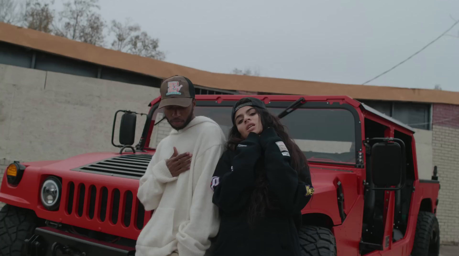 a man and woman standing next to a red jeep