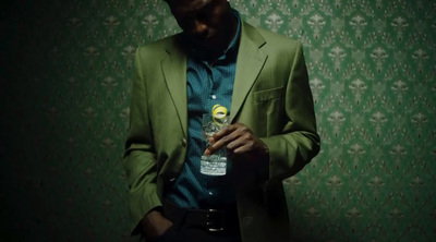 a man in a green suit is holding a bottle