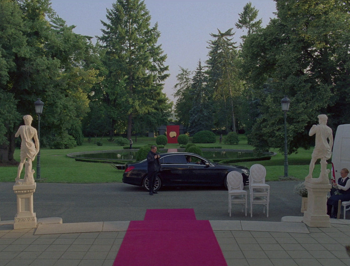 a car parked in a driveway next to statues