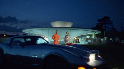 two men standing in front of a car at night